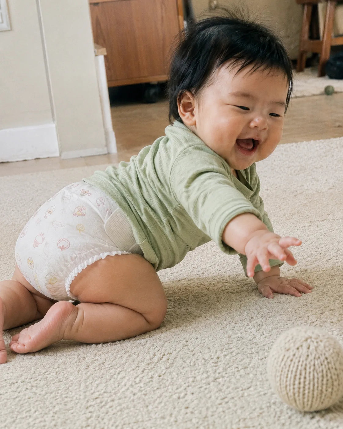 Bé bò chơi trên thảm, mặc tã dán Merria có tab dán bên hông