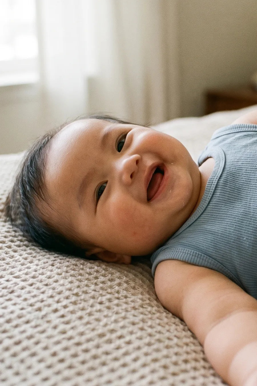 Bé nằm cười trên giường cùng tã Merria